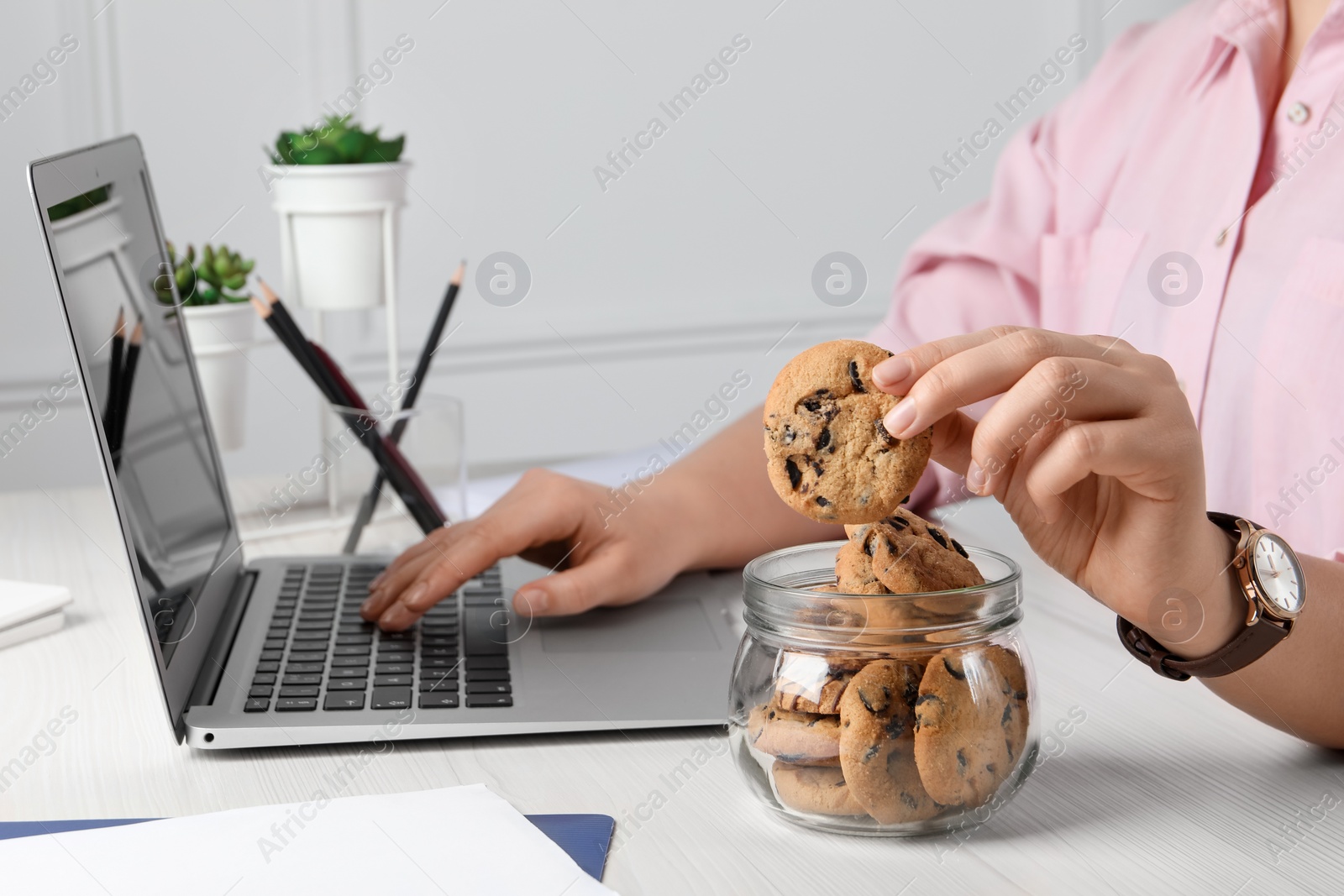 Office worker taking chocolate chip cookie from jar at workplace, closeup Photo of Office worker taking chocolate chip cookie from jar at workplace, closeup