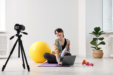 Happy sports blogger recording fitness lesson with camera at home