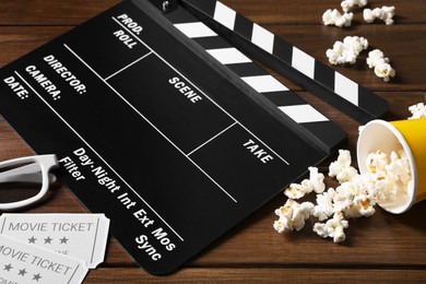 Photo of Clapperboard, movie tickets, 3D glasses and popcorn on wooden table, closeup