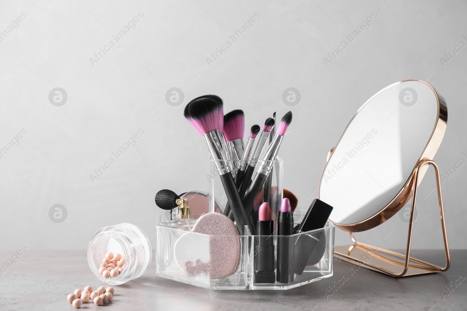 Photo of Make up brushes, cosmetic products and mirror on grey table