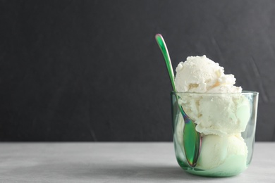 Photo of Glass with tasty vanilla ice cream on grey table