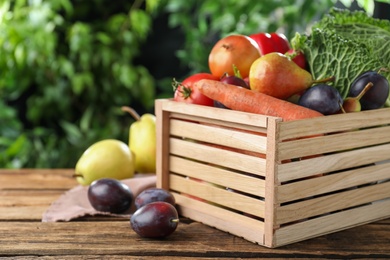 Photo of Crate full of different vegetables and fruits on wooden table outdoors, closeup. Harvesting time