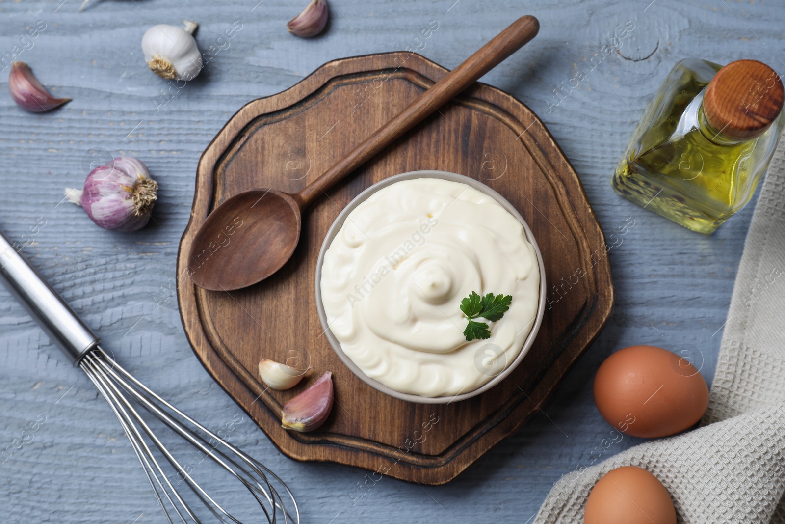 Photo of Tasty mayonnaise in bowl, ingredients and whisk on gray wooden table, flat lay