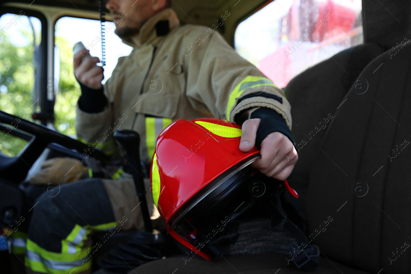 Photo of Firefighter using portable radio set while driving fire truck, selective focus