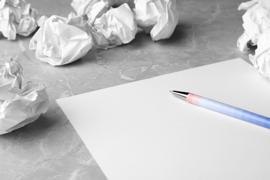 Photo of Blank sheet, pen and crumpled paper balls on grey table. Space for text