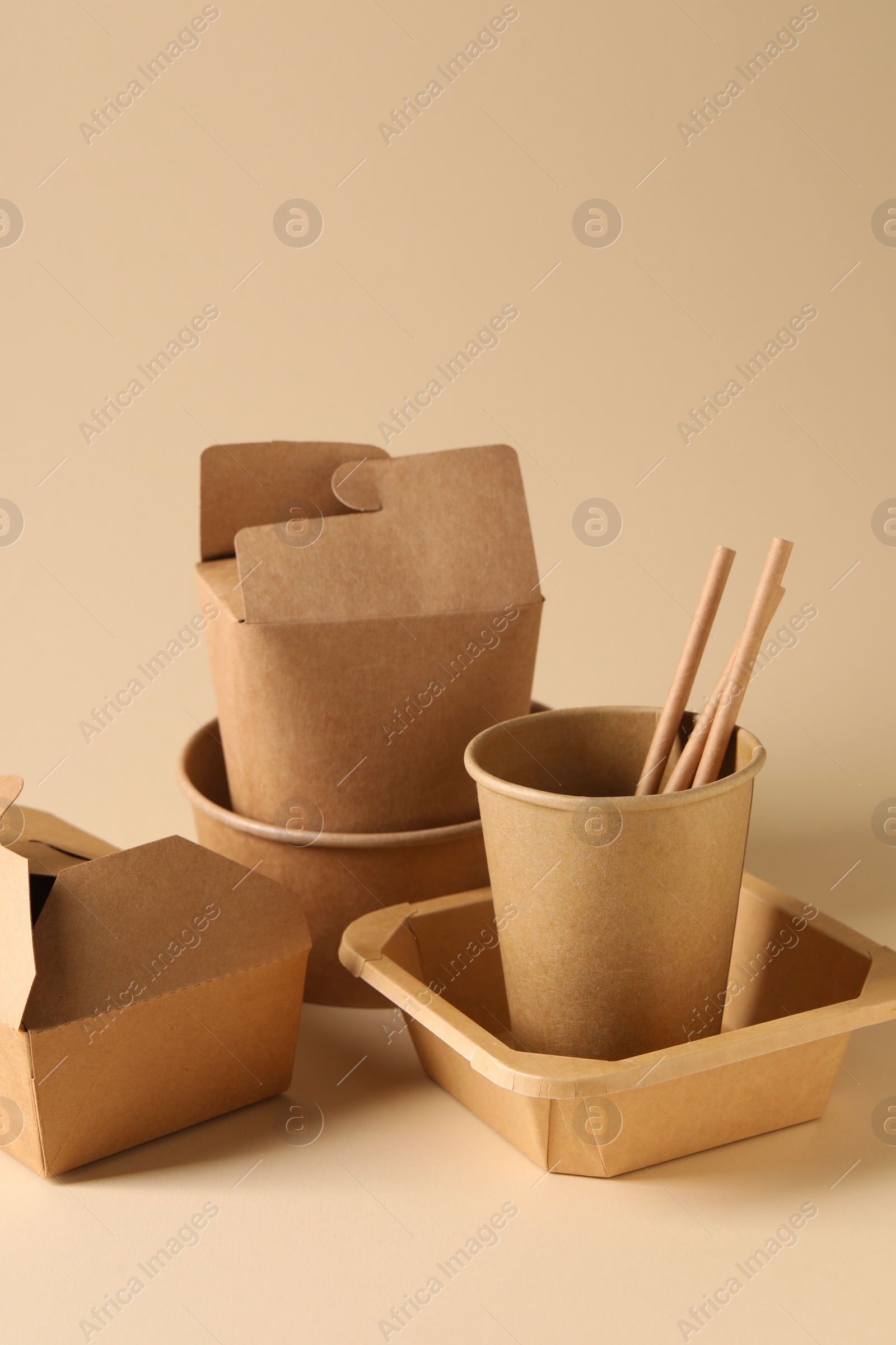 Photo of Eco friendly food packaging. Paper containers and tableware on beige background