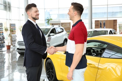 Photo of Young man buying car in salon