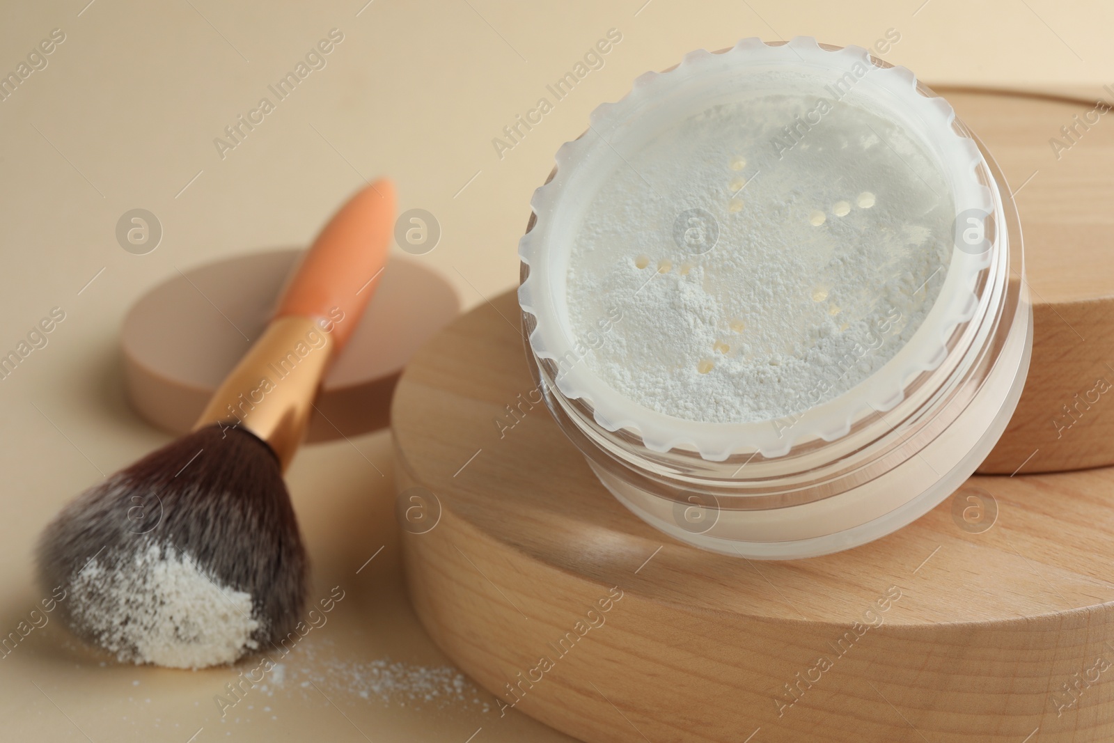 Photo of Rice loose face powder and makeup brush on beige background, closeup