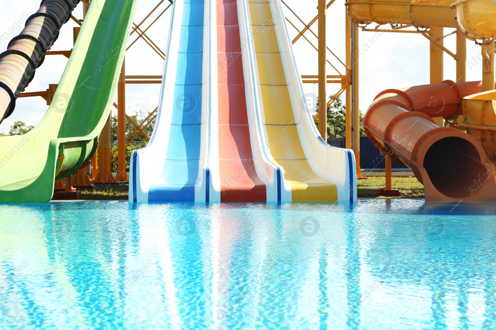 Photo of Different colorful slides and swimming pool in water park on sunny day