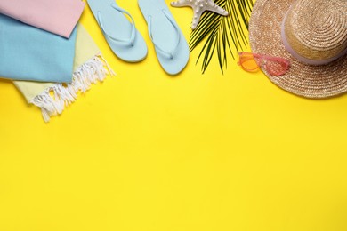 Photo of Beach towel, flip flops, straw hat and sunglasses on yellow background, flat lay. Space for text