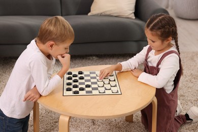 Photo of Children playing checkers at coffee table indoors