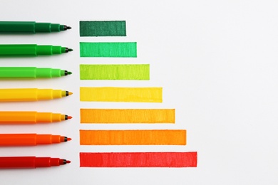 Photo of Flat lay composition with colorful markers on white background. Energy efficiency concept