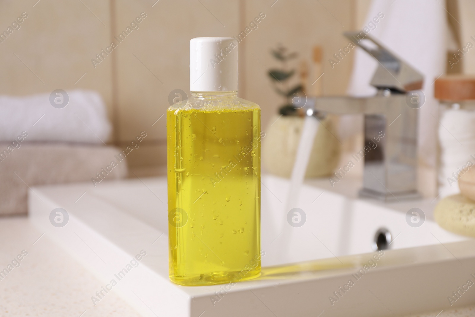 Photo of Fresh mouthwash in bottle on sink in bathroom, closeup