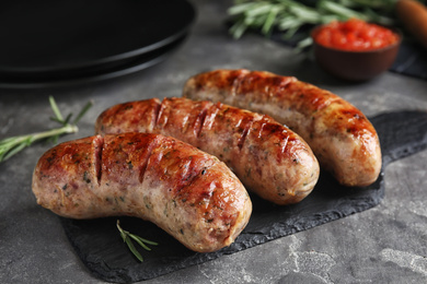 Photo of Tasty grilled sausages on grey table, closeup