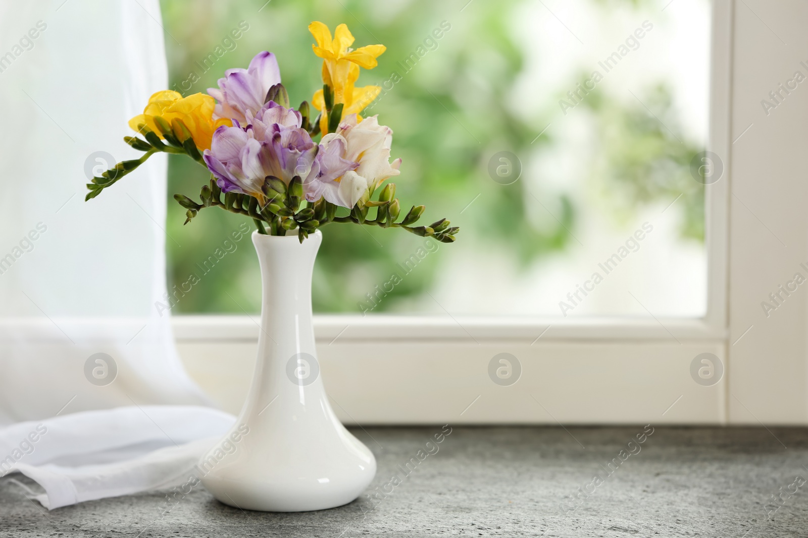 Photo of Beautiful fresh freesias on window sill indoors. Spring flowers