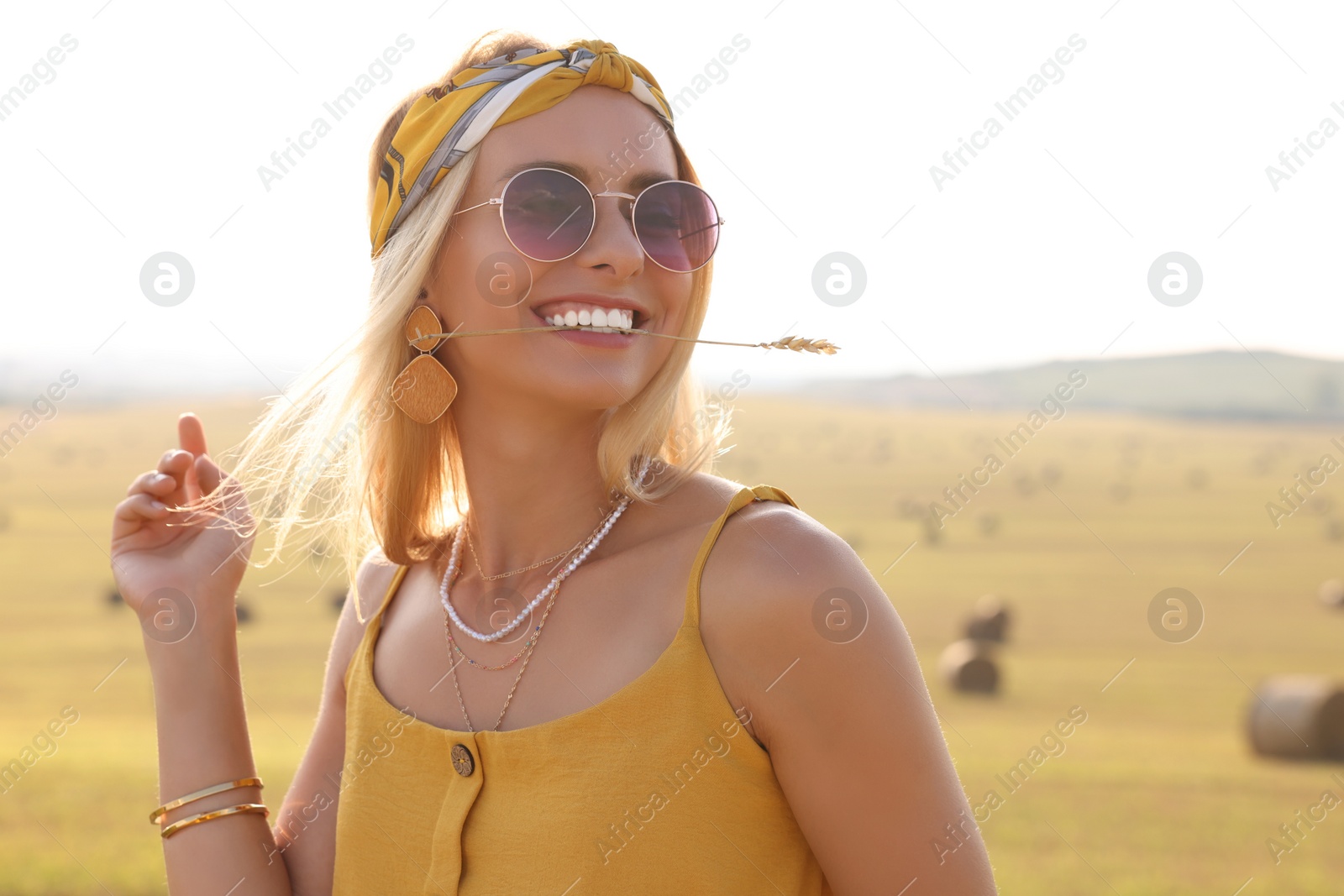 Photo of Beautiful happy hippie woman with spikelet in field, space for text