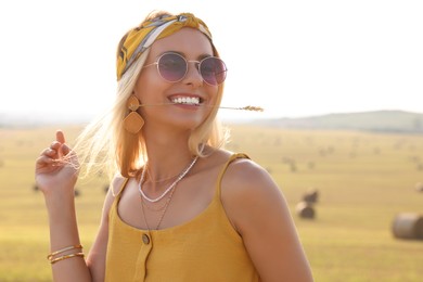 Beautiful happy hippie woman with spikelet in field, space for text