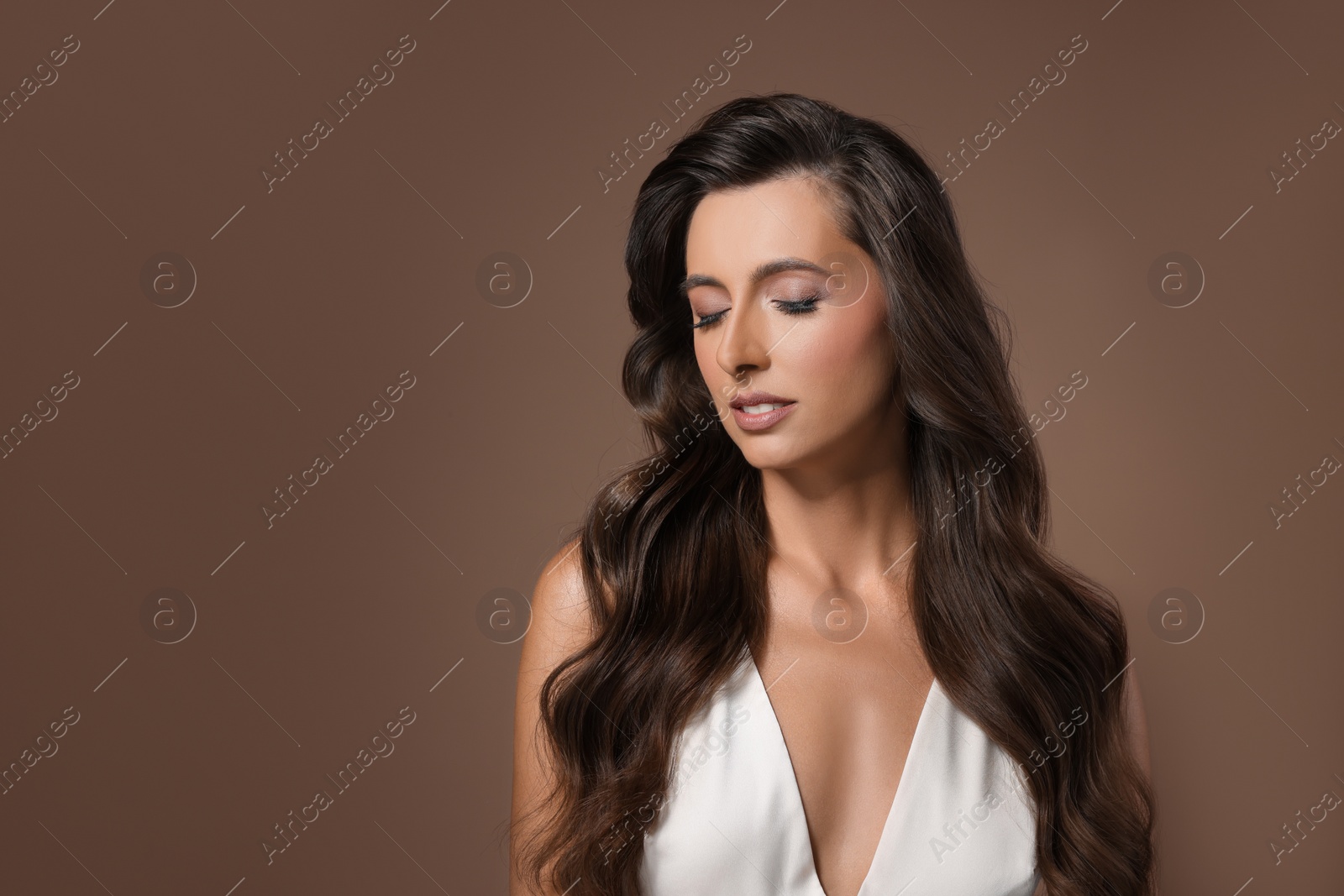 Photo of Hair styling. Beautiful woman with wavy long hair on brown background, space for text