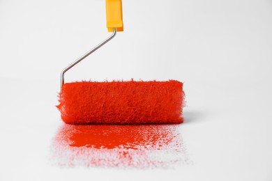 Photo of Roller brush and strokes of orange paint on white background
