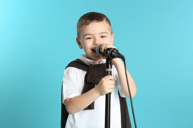 Photo of Cute funny boy with microphone on color background