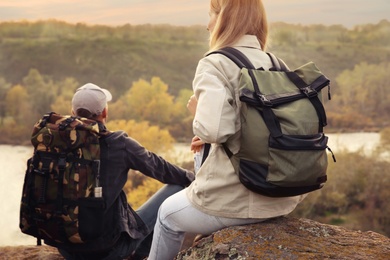 Photo of Group of friends with backpacks near mountain river, back view