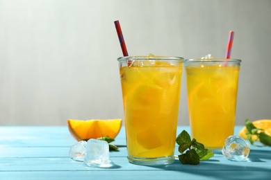 Delicious orange soda water on light blue wooden table. Space for text