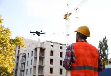 Builder operating drone with remote control at construction site. Aerial survey