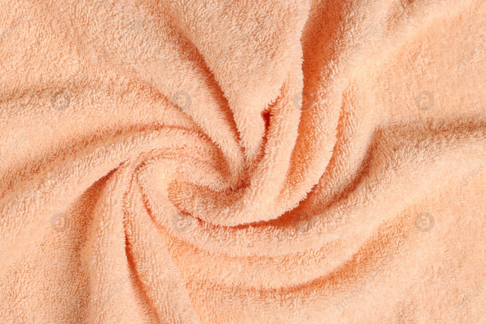 Photo of Soft crumpled pale orange towel as background, top view