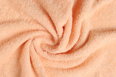 Photo of Soft crumpled pale orange towel as background, top view