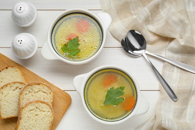 Delicious bouillon served on white wooden table, flat lay