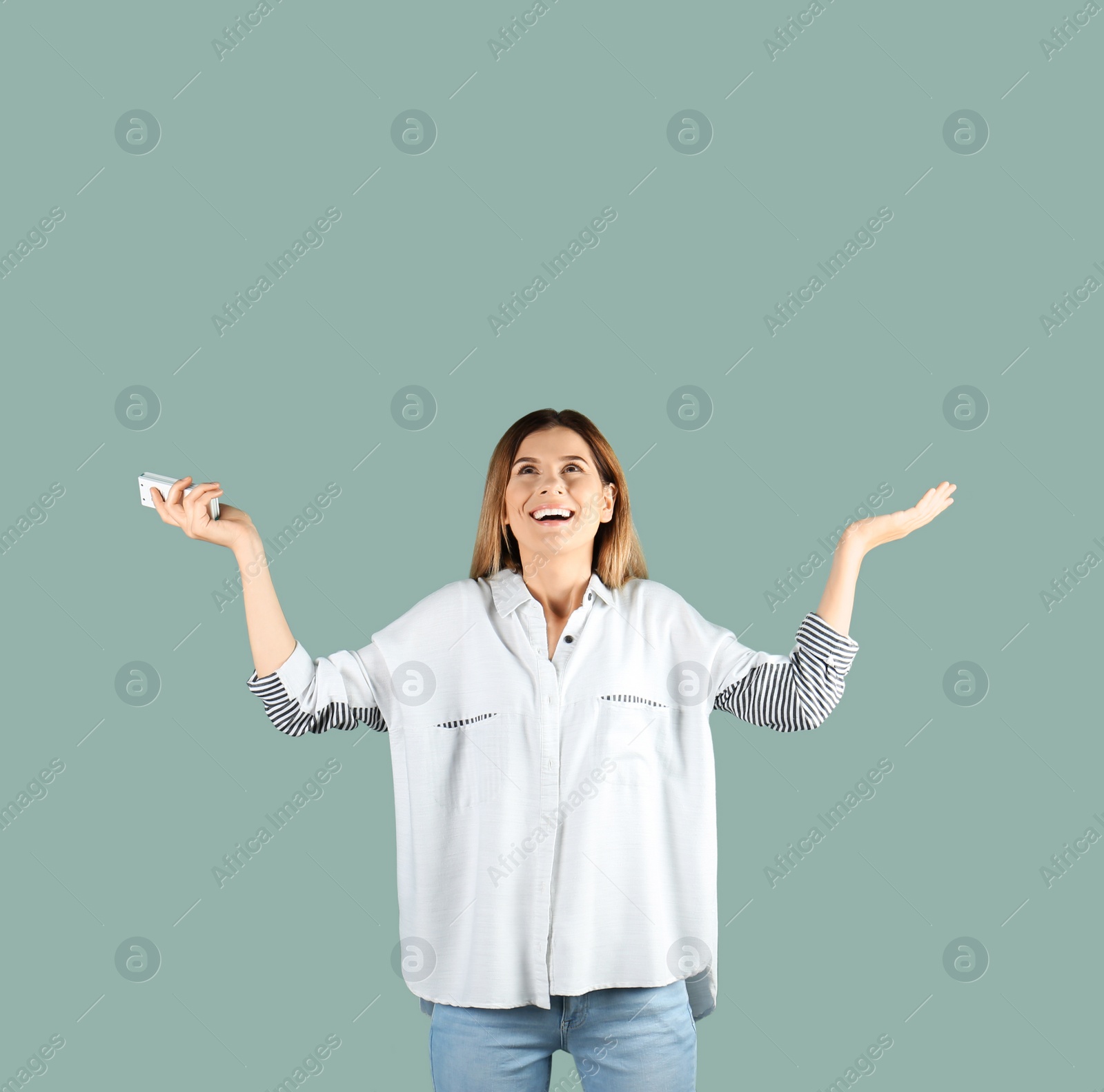 Photo of Happy woman with air conditioner remote on color background