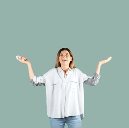 Happy woman with air conditioner remote on color background