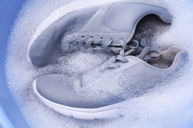 Photo of Washing sport shoes in plastic basin, top view
