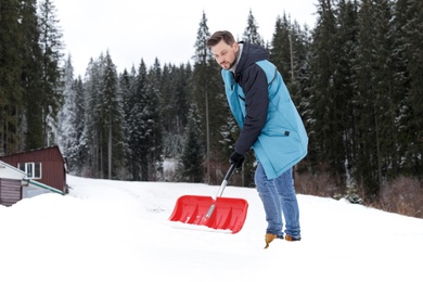 Man removing snow with shovel near house. Space for text