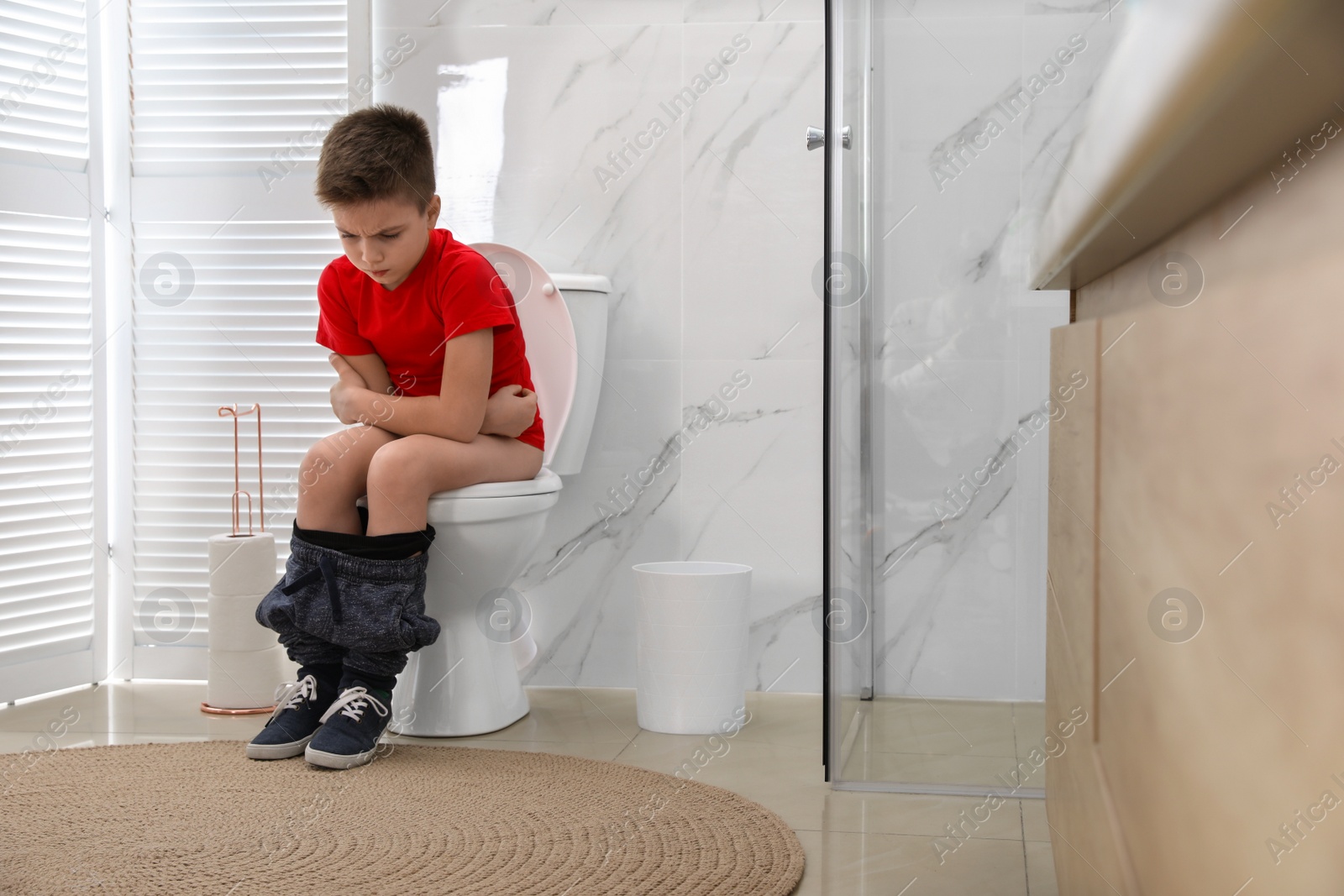 Photo of Boy suffering from hemorrhoid on toilet bowl in rest room