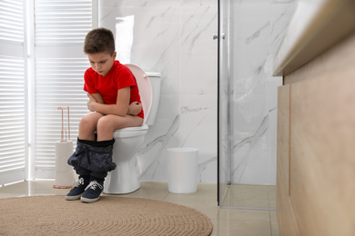 Boy suffering from hemorrhoid on toilet bowl in rest room