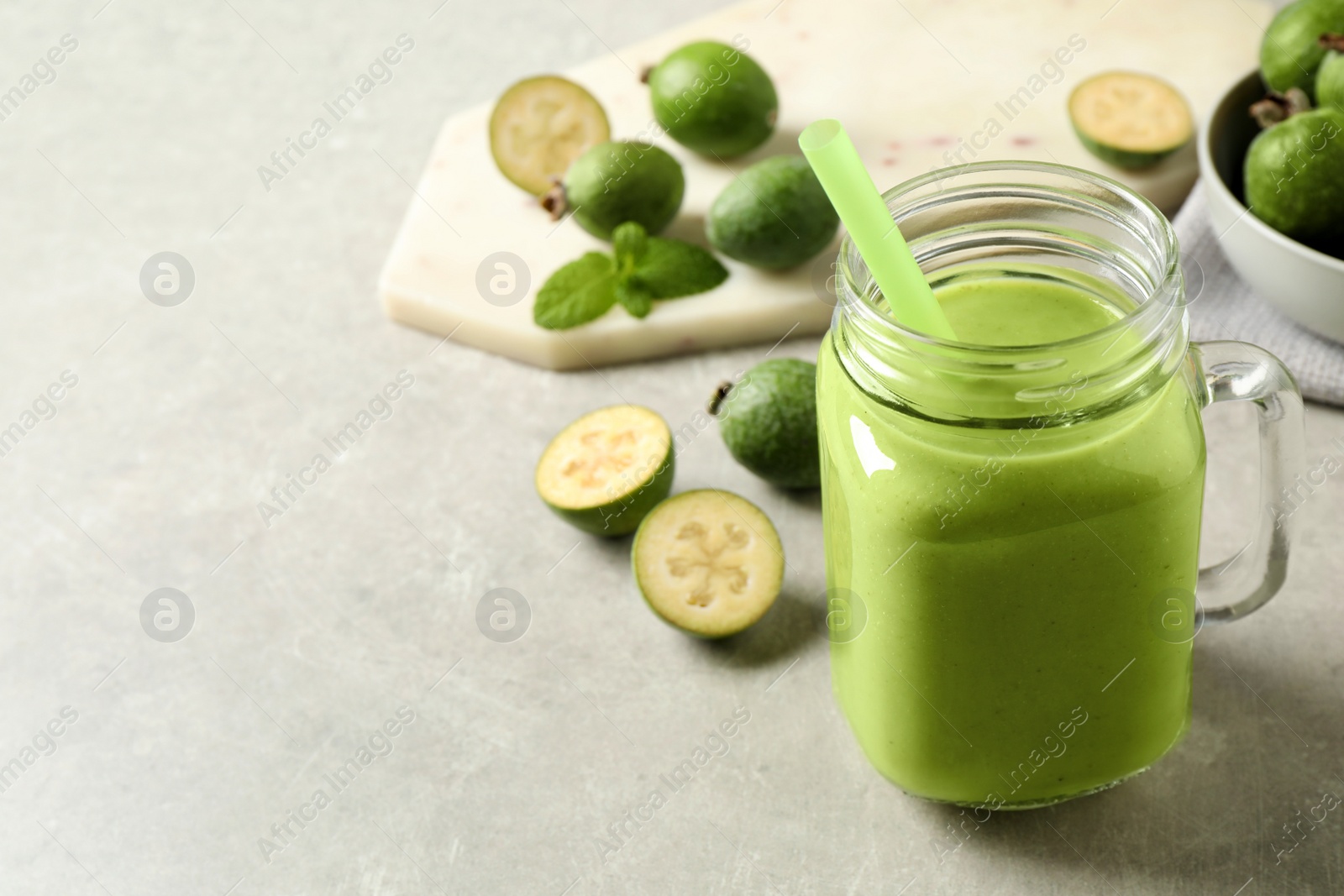 Photo of Fresh feijoa smoothie in mason jar on light table, closeup. Space for text