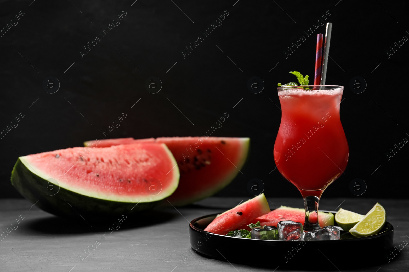 Photo of Tasty watermelon drink with mint on grey table against black background