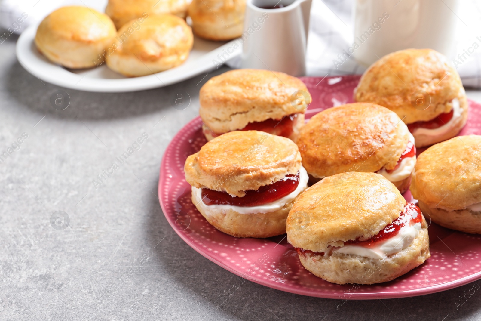 Photo of Tasty scones with clotted cream and jam on plate, closeup