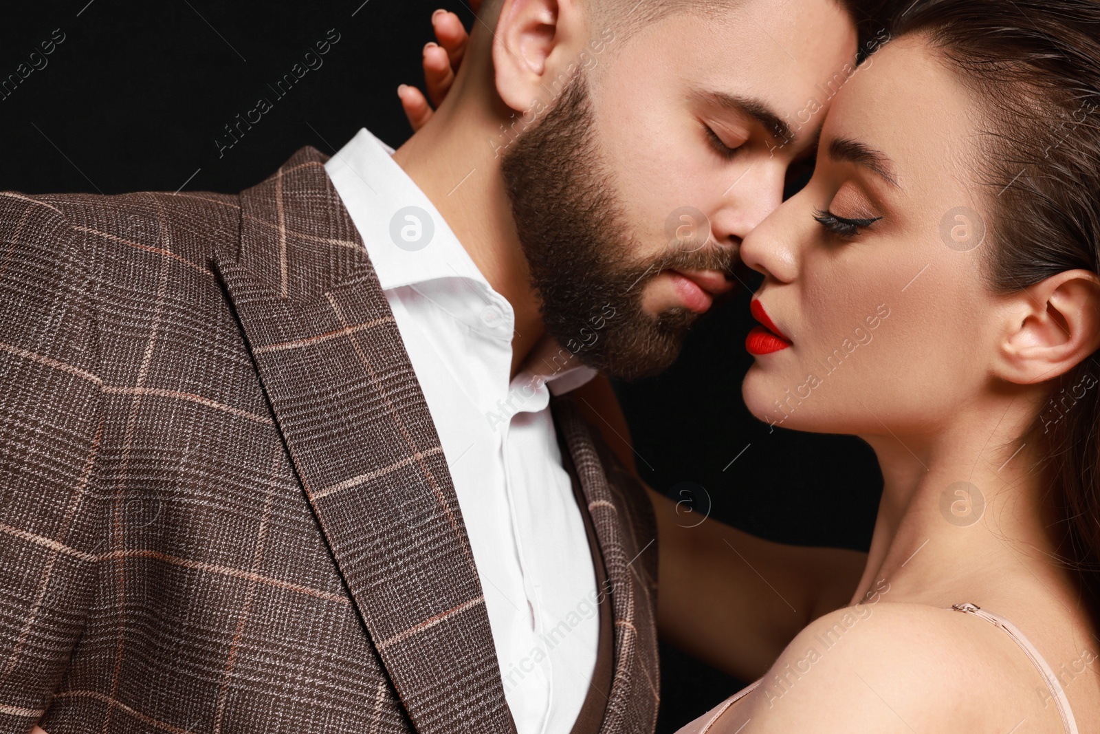 Photo of Handsome bearded man with sexy lady on black background, closeup