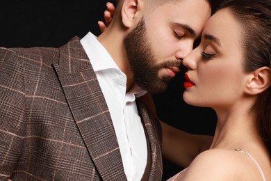 Handsome bearded man with sexy lady on black background, closeup