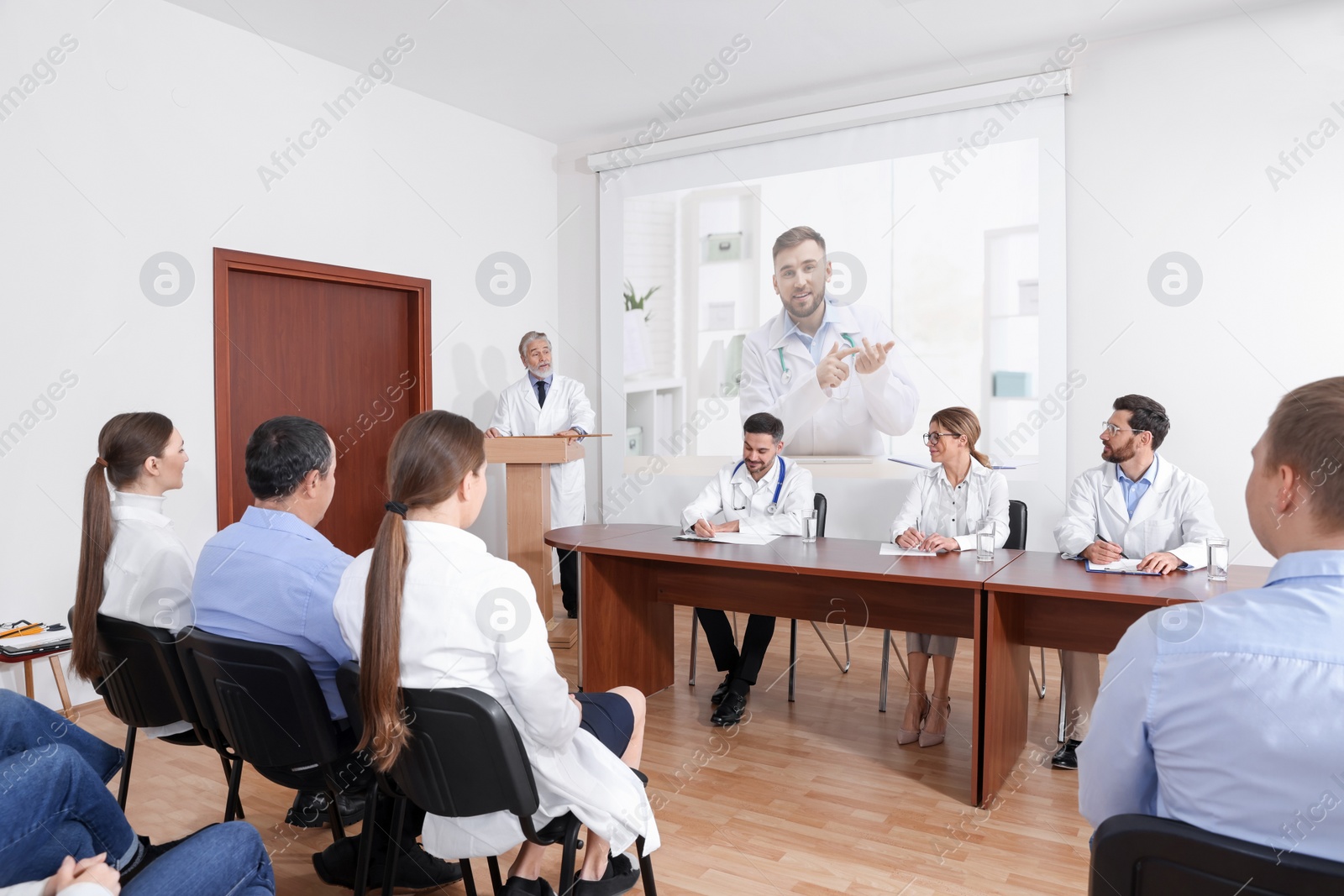 Image of Lecture with online participant. Doctors in meeting room. Using projector for videoconference