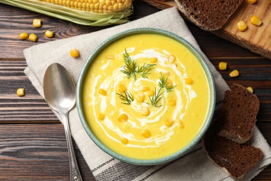Photo of Delicious creamy corn soup served on wooden table, flat lay