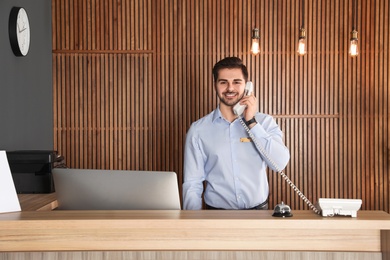Receptionist talking on phone at desk in lobby