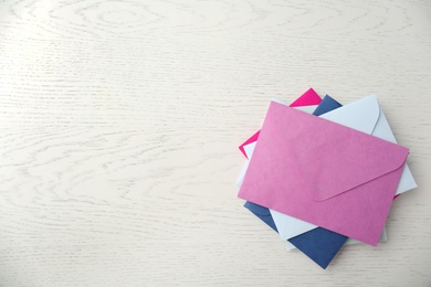 Colorful paper envelopes on white wooden background, top view. Space for text