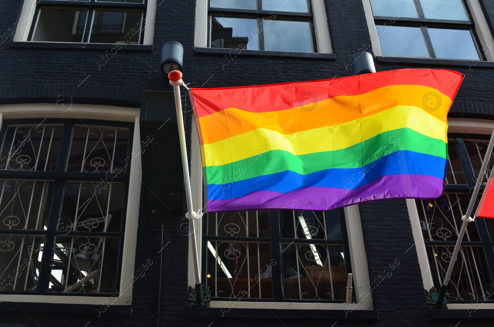 Photo of Rainbow flag fluttering on modern building outdoors