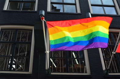 Rainbow flag fluttering on modern building outdoors