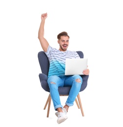 Photo of Emotional young man with laptop in armchair on white background