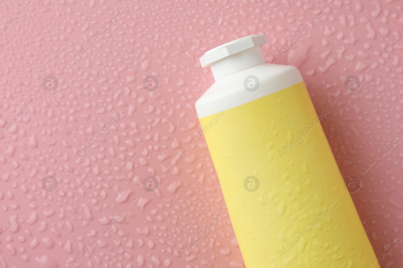 Photo of Moisturizing cream in tube on pink background with water drops, top view. Space for text