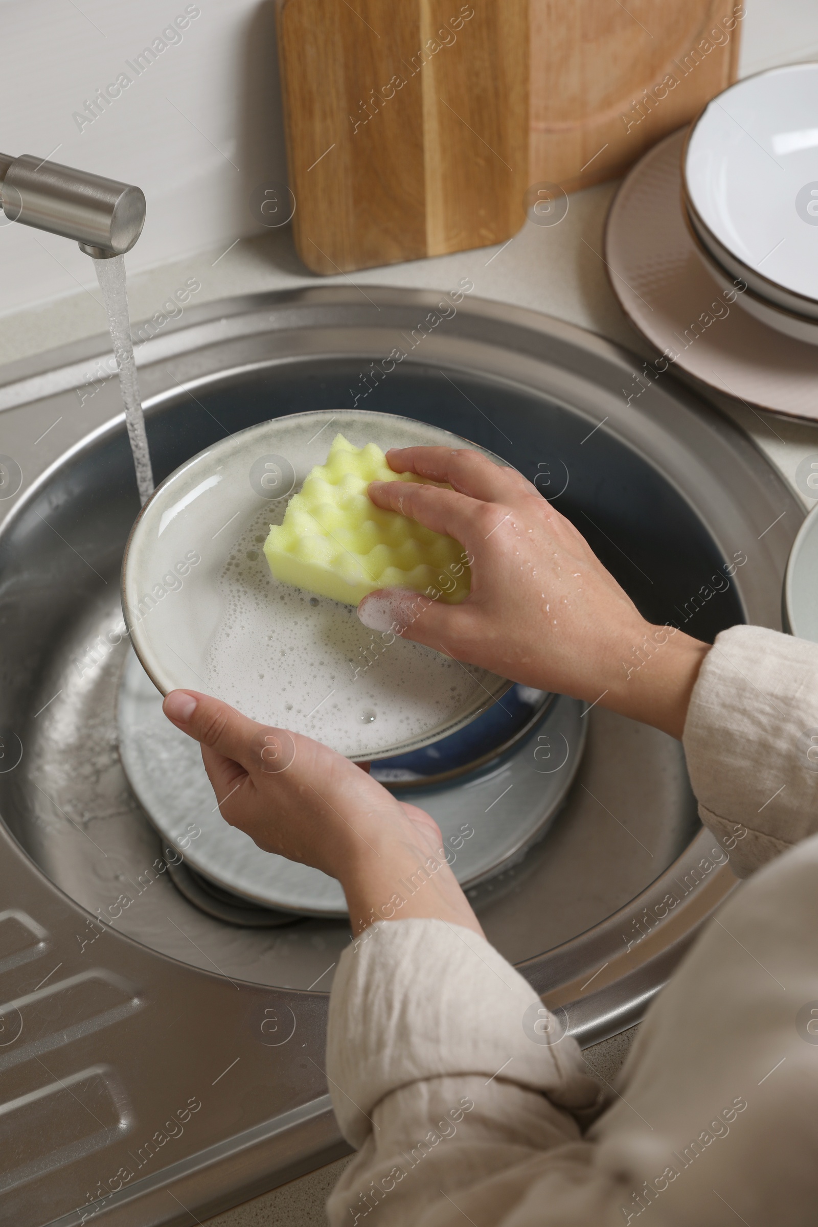 Photo of Woman washing plate in kitchen sink, above view